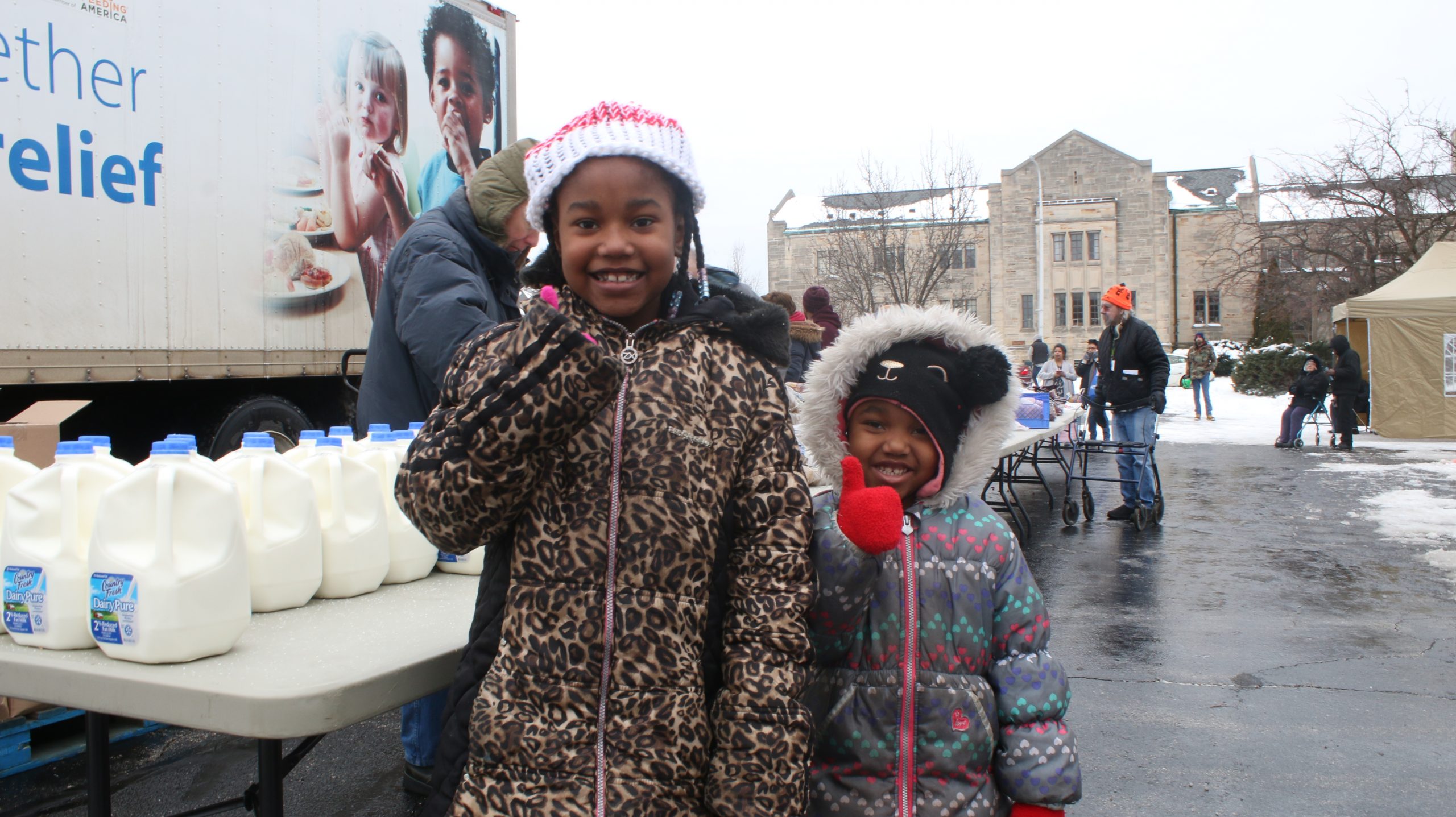 Two little girls smile at the camera while waiting at the Mobile Pantry