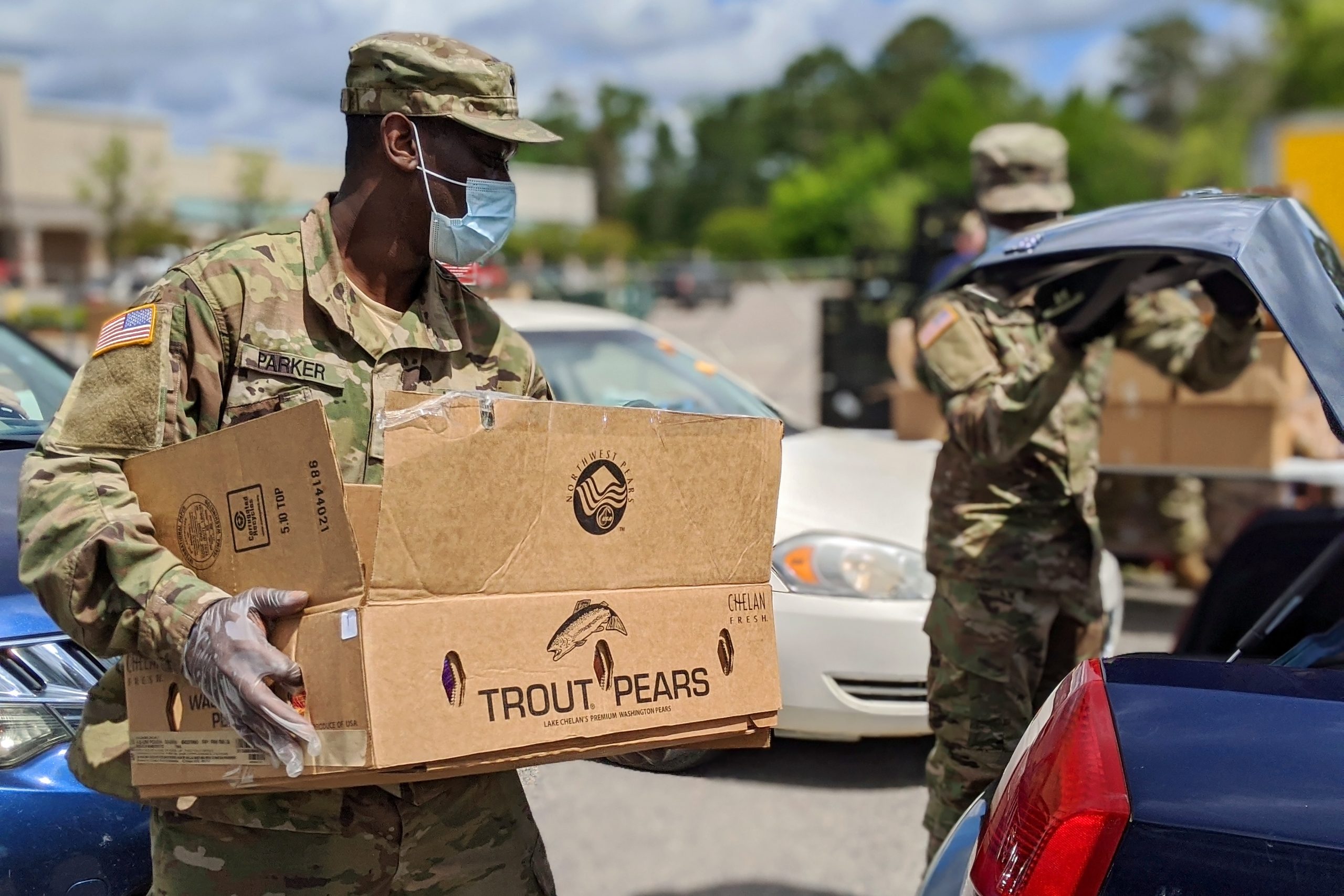 National guard member helps at a drive-thru food distribution.