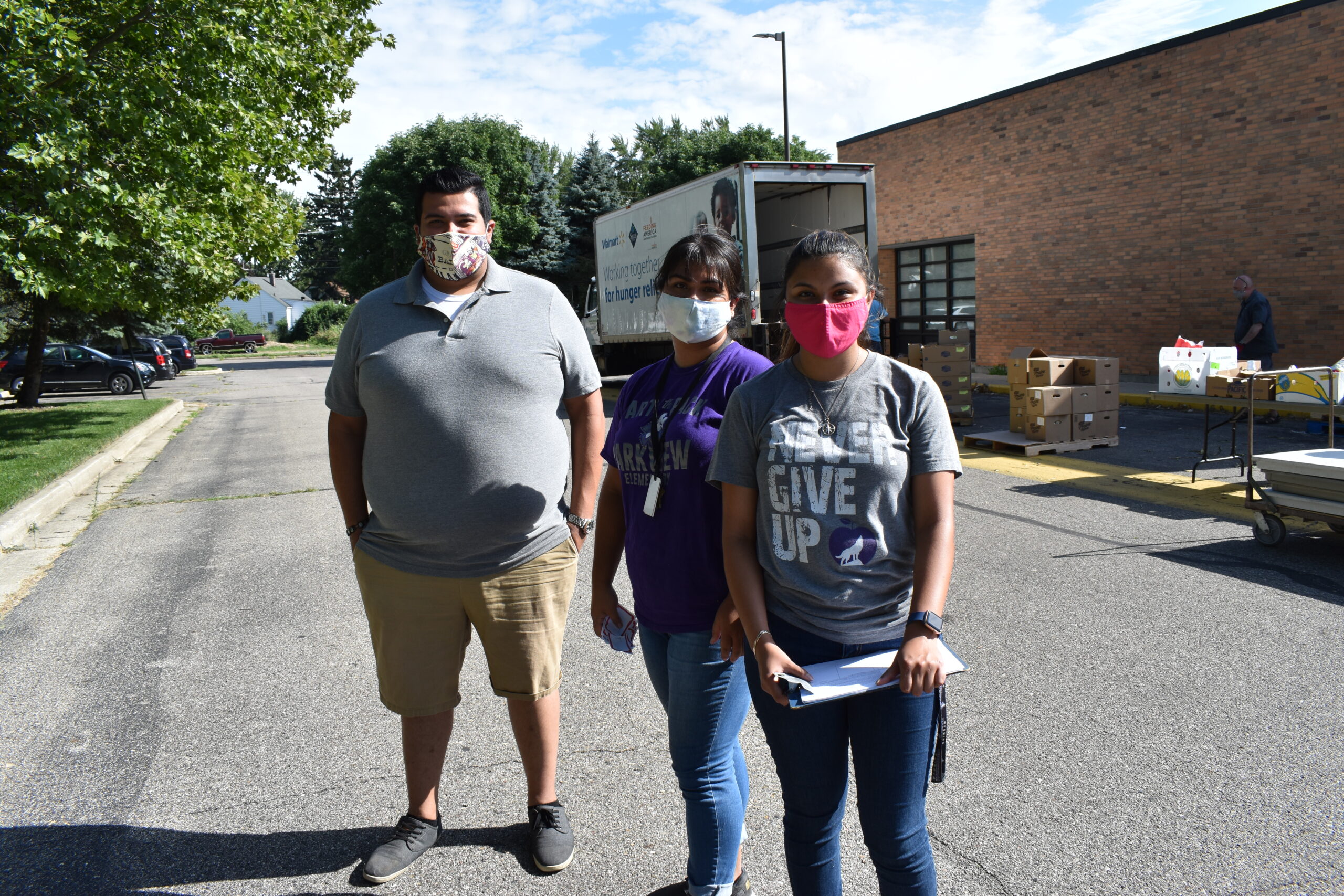 The three community coordinators stand in front of a Mobile Pantry