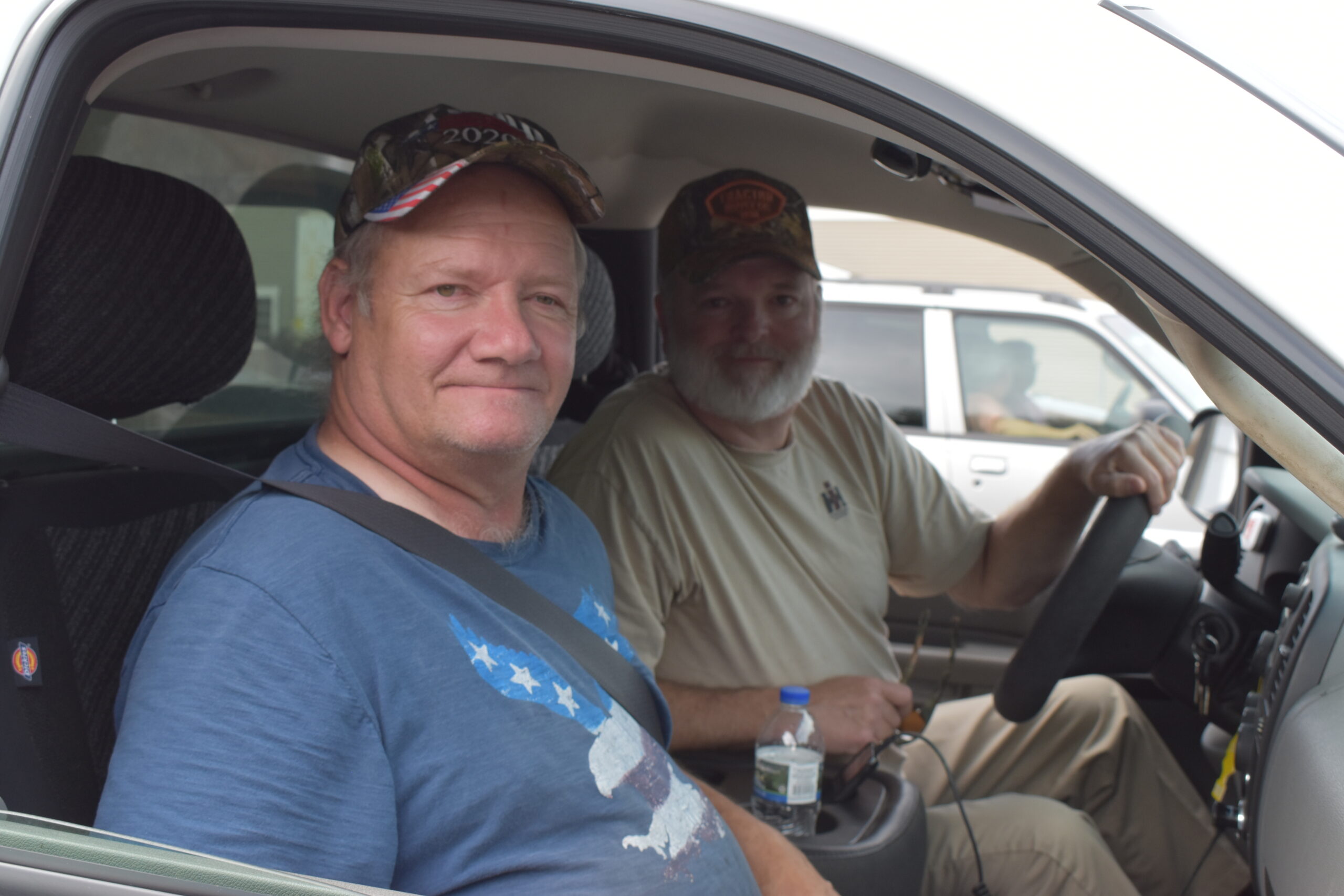 Two men sit in a car waiting for a mobile pantry