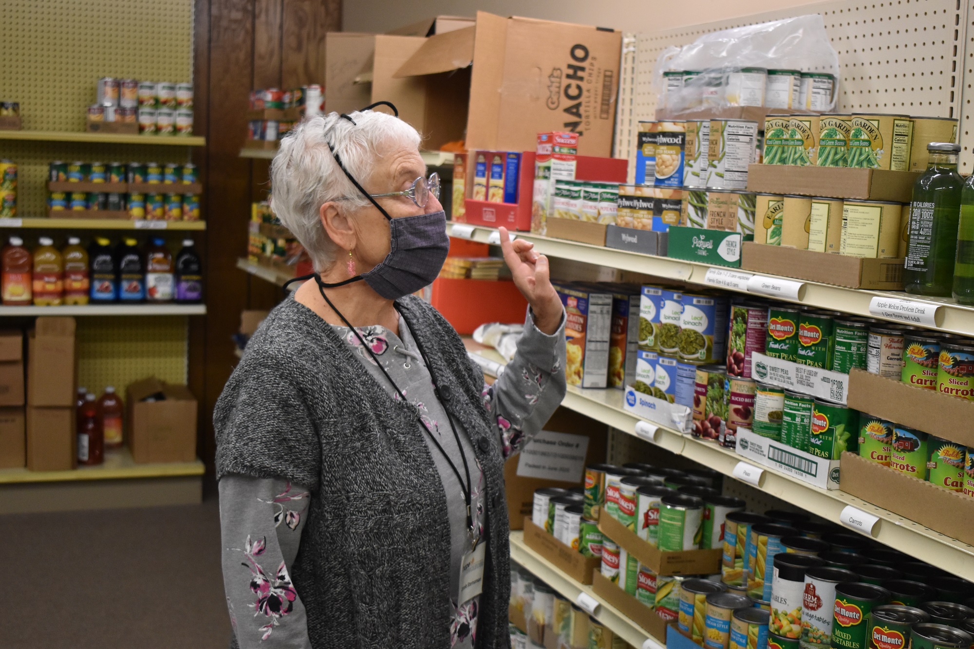 Carole stands in front of shelves of food at the pantry