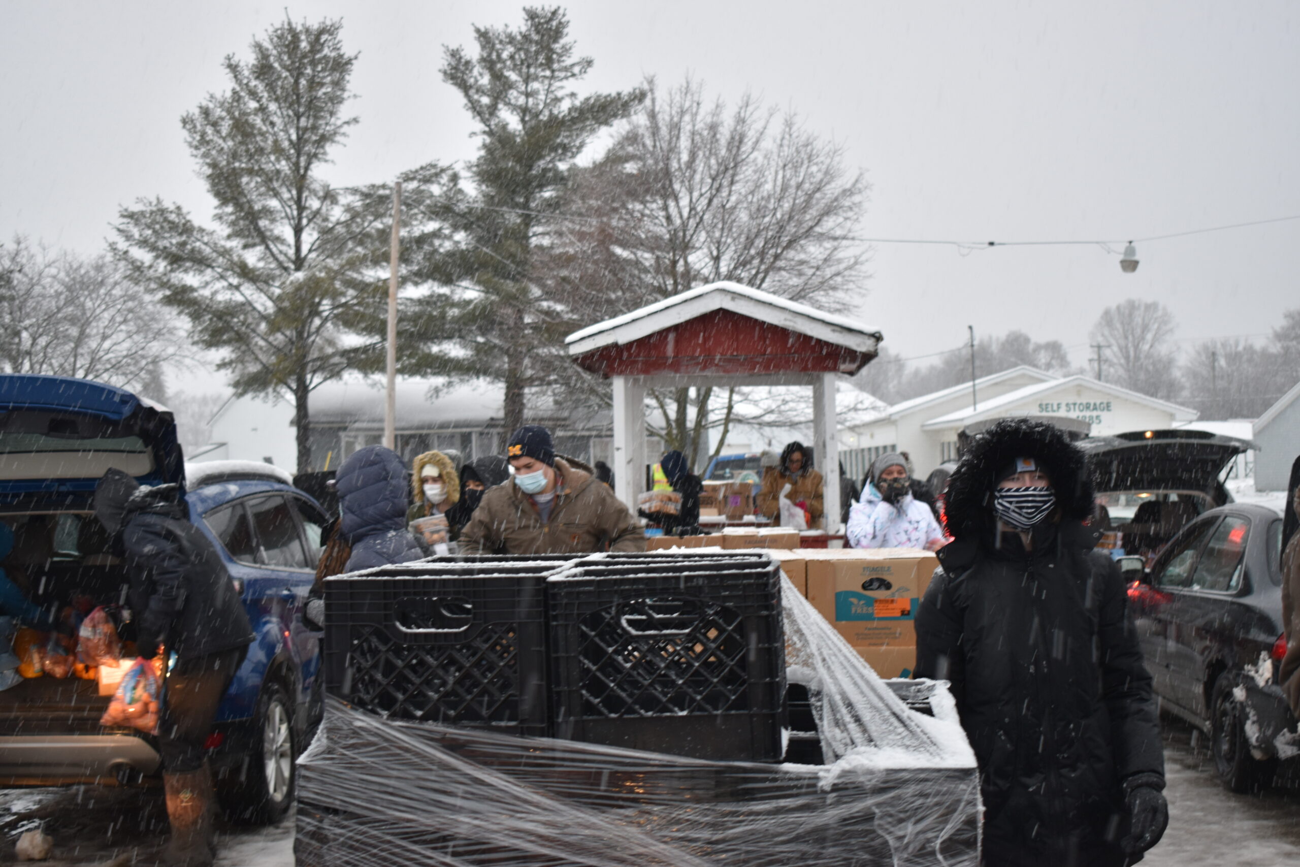 Volunteers load cars with food amid a snowy backdrop