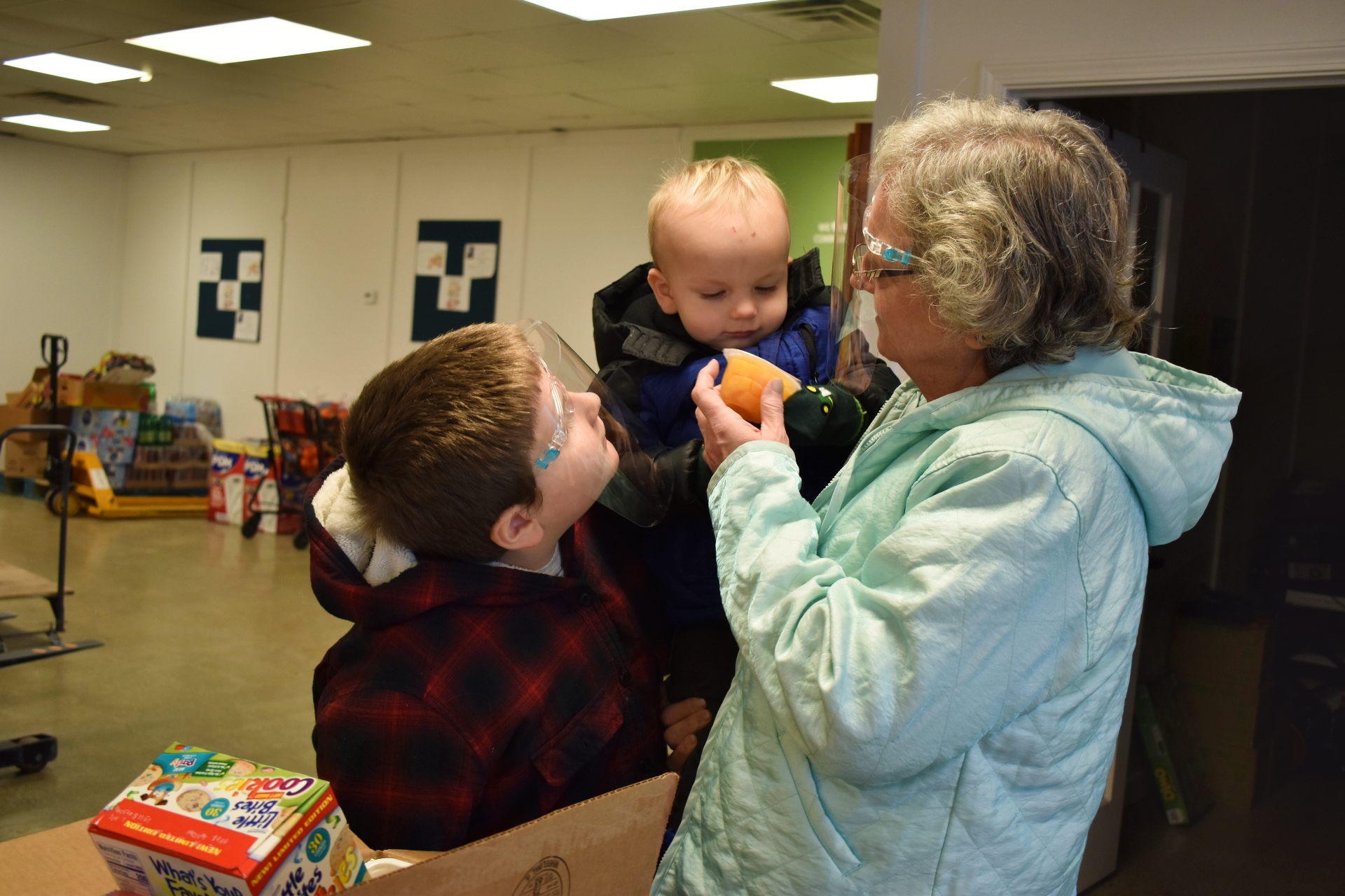 A grandma and her two grandkids look at food they've received
