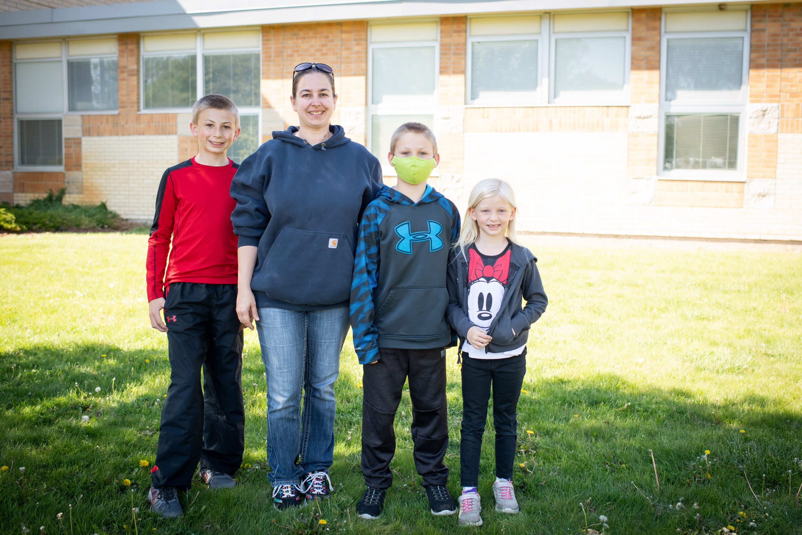 April stands with her three children in front of the school