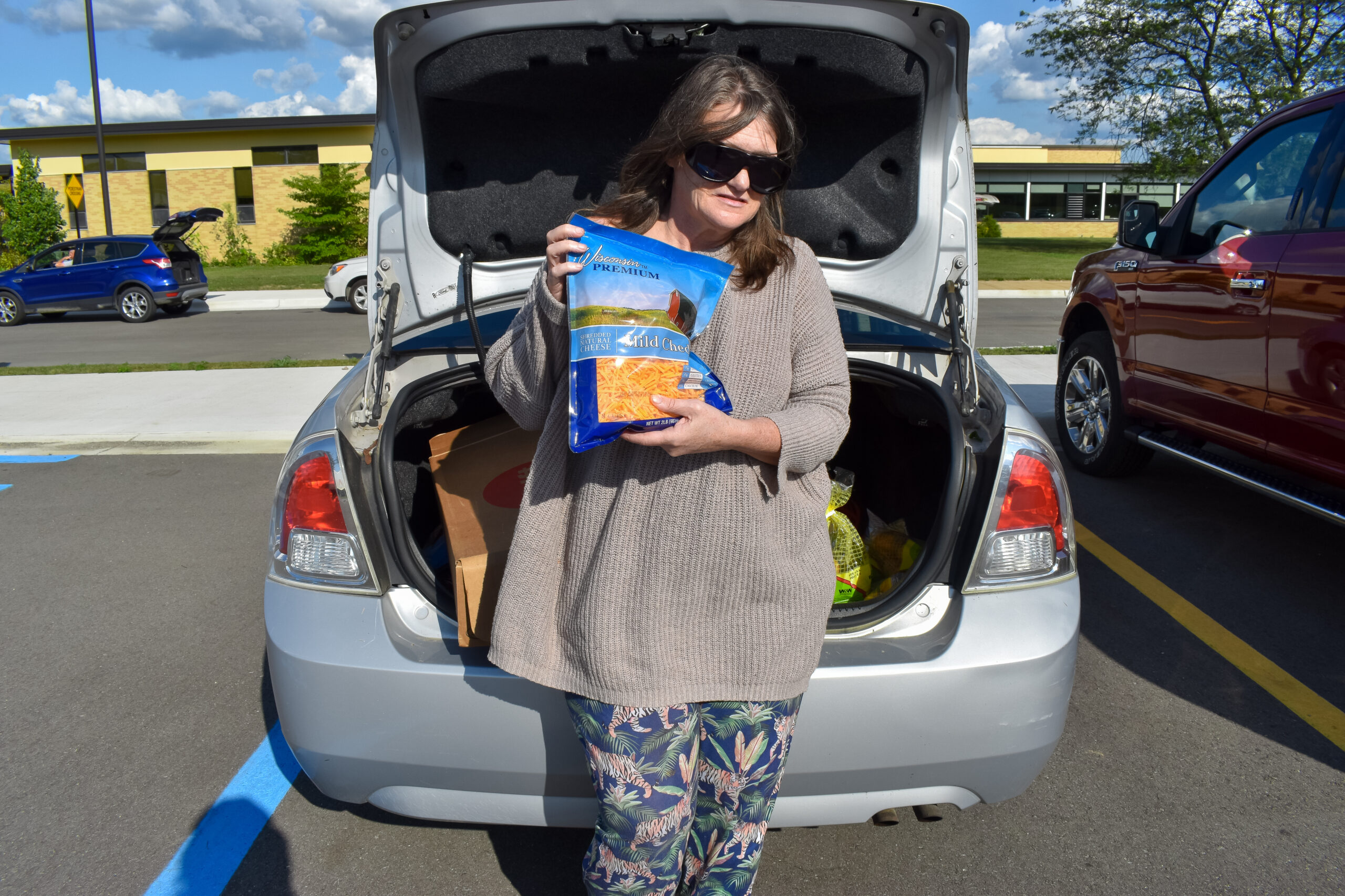 A woman poses with cheese and other food she received from the Mobile Pantry